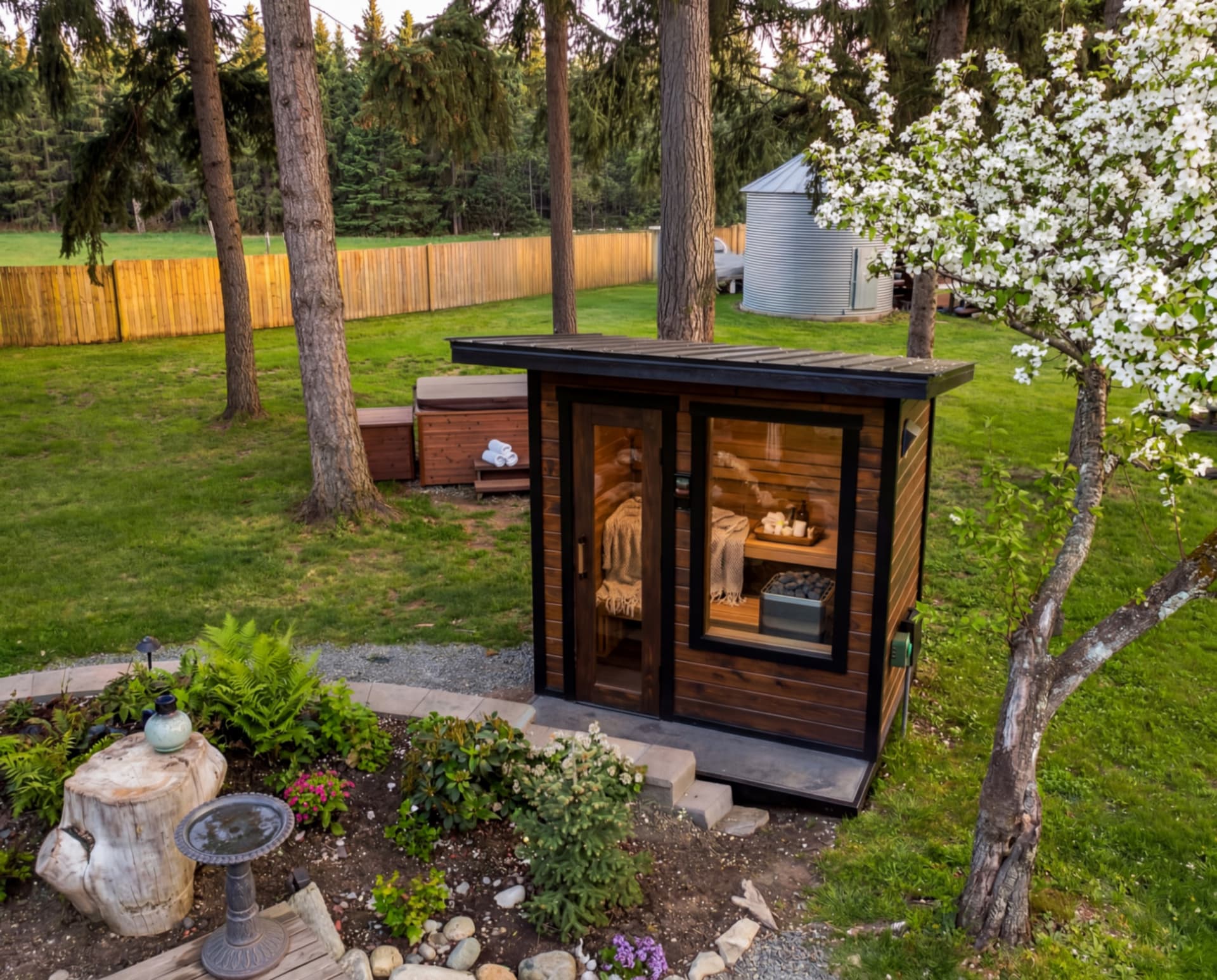 Aerial view of the Yutori backyard: cedar sauna, garden beds, stone water feature, and wooden footbridge